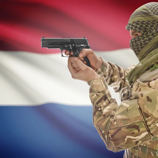 Male with gun in hands and national flag on background - Netherlands — Stock Photo, Image