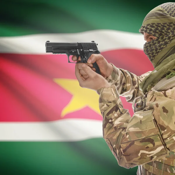 Male with gun in hands and national flag on background - Suriname — Stock Photo, Image