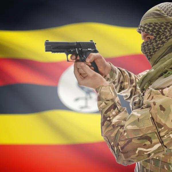 Male with gun in hands and national flag on background - Uganda — ストック写真