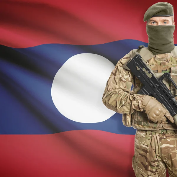 Katona géppuskával és háttér - zászlót Laosz — Stock Fotó