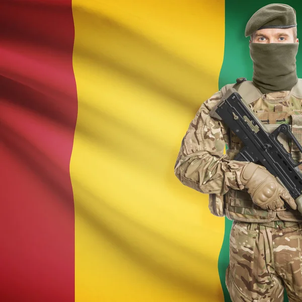 Soldier with machine gun and flag on background - Guinea — Stock Photo, Image