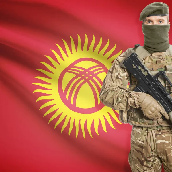 Soldier with machine gun and flag on background - Kyrgyzstan — Stock Photo, Image