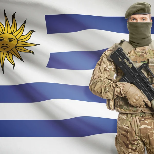 Солдат с автоматом и флагом на фоне - Уругвай — стоковое фото