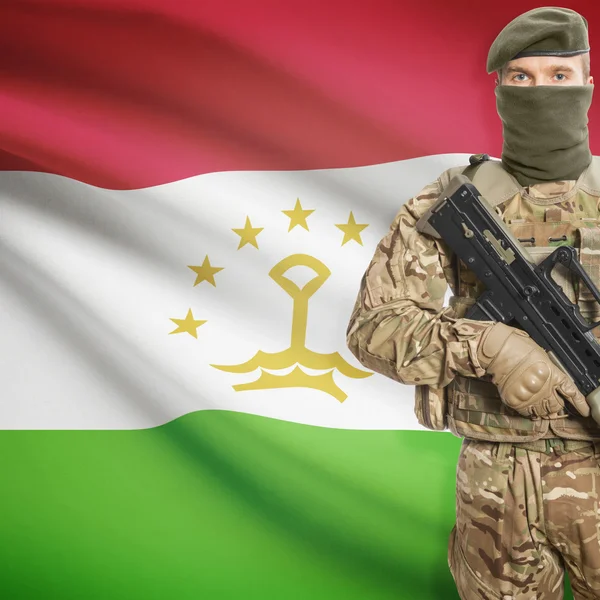 Солдат с автоматом и флагом на фоне - Таджикистан — стоковое фото