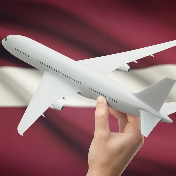 Flugzeug in der Hand mit Flagge auf Hintergrund-Serie - Lettland — Stockfoto