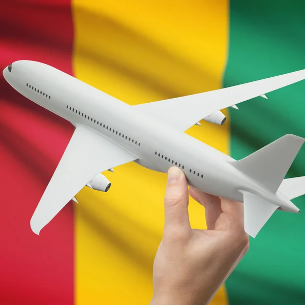 Avión en la mano con la bandera en la serie del fondo - Guinea —  Fotos de Stock