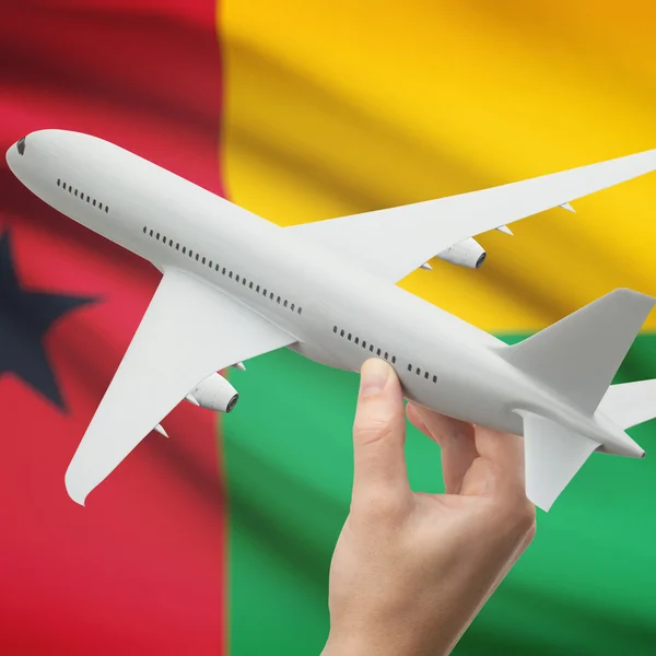 Vliegtuig in hand met vlag op achtergrond serie - Guinee-Bissau — Stockfoto