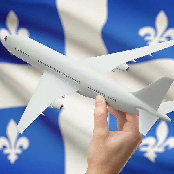 Самолет в руке с канадским флагом провинции на фоне серии - Квебек — стоковое фото