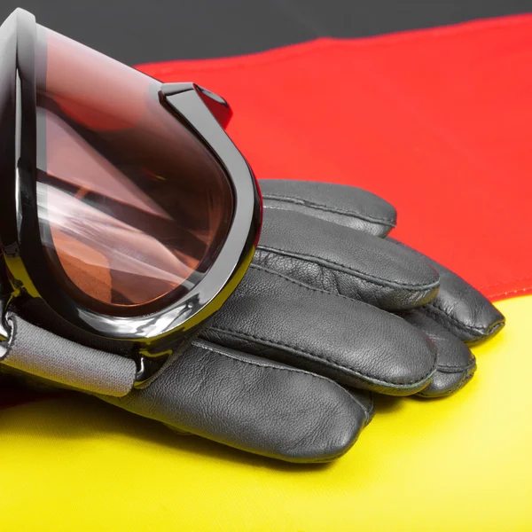 Winter sport goggles and leather gloves over German flag — Stock Photo, Image