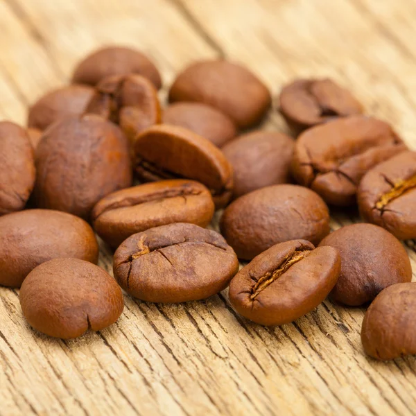 Close up of coffee beans on old wooden table — Stock Photo, Image