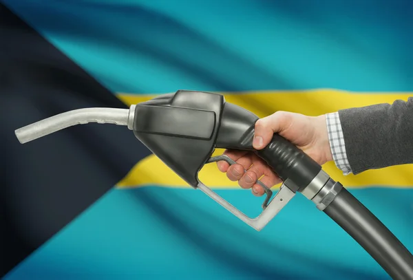 Fuel pump nozzle in hand with national flag on background - Bahamas — Stock Photo, Image