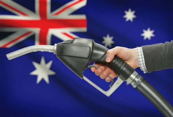 Üzemanyag szivattyú fúvóka a kezében, a háttér - Ausztrália zászlaja — Stock Fotó