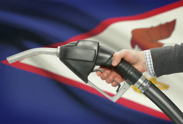 Ugello della pompa di carburante in mano con la bandiera nazionale su priorità bassa - Samoa americane — Foto Stock