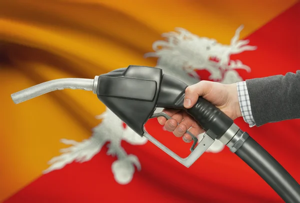 Gicleur de pompe de carburant dans la main avec un drapeau national sur fond - Bhoutan — Photo