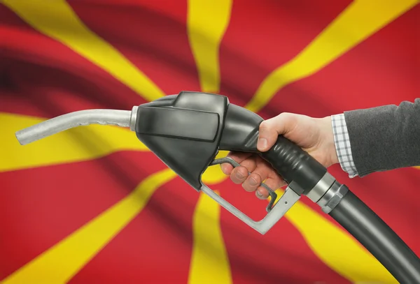 Bocal da bomba de combustível na mão com a bandeira nacional no plano de fundo - Macedónia — Fotografia de Stock