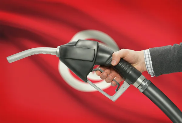 Bocal da bomba de combustível na mão com a bandeira nacional no plano de fundo - Tunísia — Fotografia de Stock