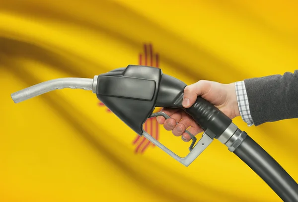 Fuel pump nozzle in hand with USA states flags on background - New Mexico — 图库照片