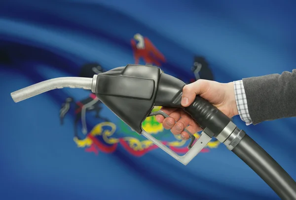 Fuel pump nozzle in hand with USA states flags on background - Pennsylvania — 图库照片