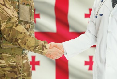 Military man in uniform and doctor shaking hands with national flag on background - Georgia