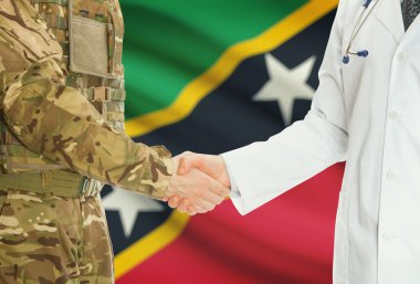 Military man in uniform and doctor shaking hands with national flag on background - Saint Kitts and Nevis