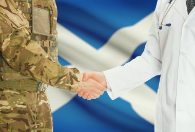 Military man in uniform and doctor shaking hands with national flag on background - Scotland