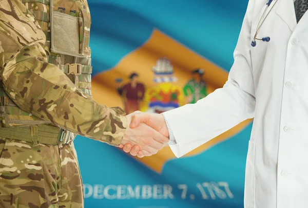 Military man in uniform and doctor shaking hands with US states flags on background - Delaware — Stok fotoğraf