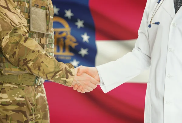 Homme militaire en uniforme et le médecin se serrant la main avec nous drapeaux d'états sur fond - Géorgie — Photo
