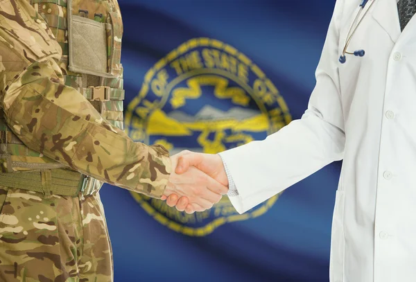 Military man in uniform and doctor shaking hands with US states flags on background - Nebraska — 图库照片