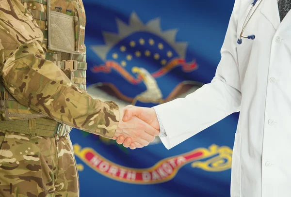 Homme militaire en uniforme et le médecin se serrant la main avec nous drapeaux d'états sur fond - Dakota du Nord — Photo