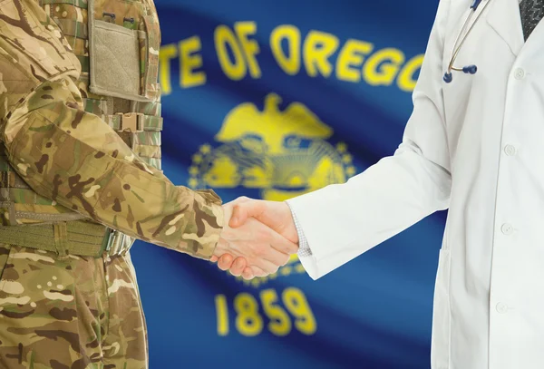 Military man in uniform and doctor shaking hands with US states flags on background - Oregon — Zdjęcie stockowe