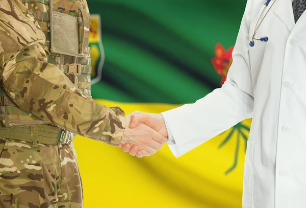 Military man in uniform and doctor shaking hands with Canadian provincies and territories flags on background - Saskatchewan — Stock Photo, Image