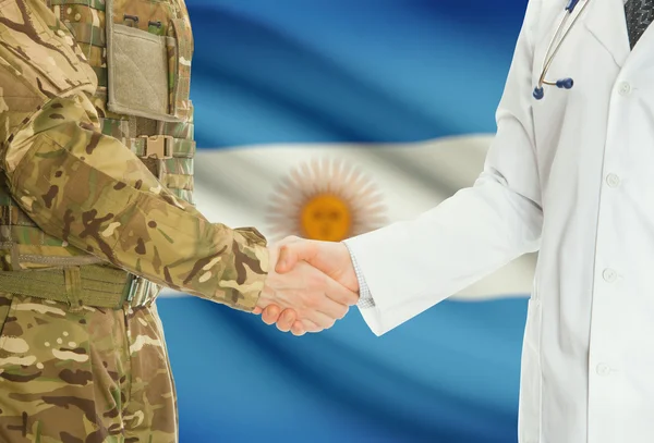 Homme militaire en uniforme et le médecin se serrant la main avec le drapeau national sur le fond - Argentine — Photo