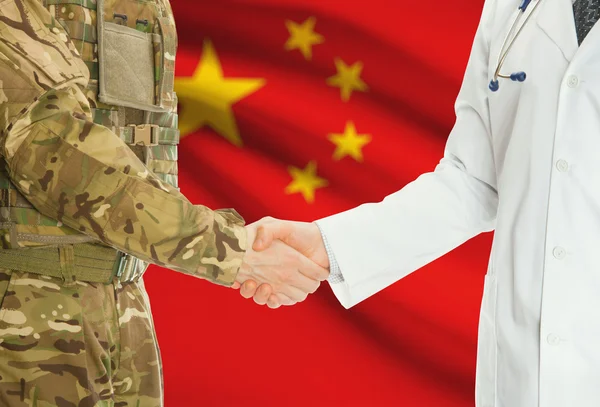 Military man in uniform and doctor shaking hands with national flag on background - China — Foto Stock