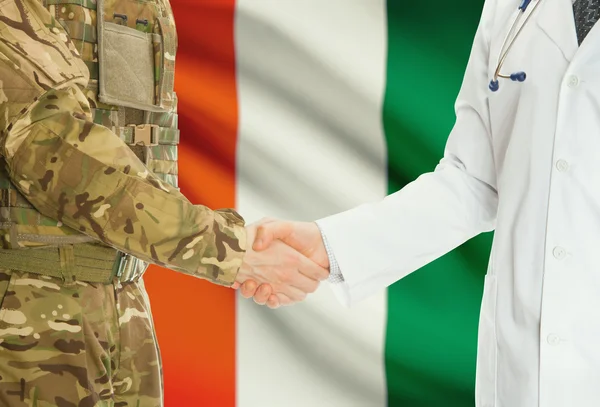 Military man in uniform and doctor shaking hands with national flag on background - Ivory Coast — Fotografia de Stock