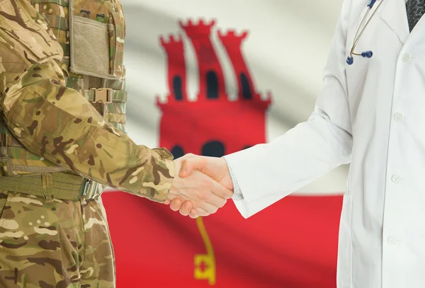 Military man in uniform and doctor shaking hands with national flag on background - Gibraltar — Stok fotoğraf