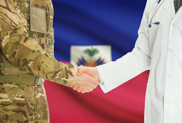 Military man in uniform and doctor shaking hands with national flag on background - Haiti — Stock Photo, Image