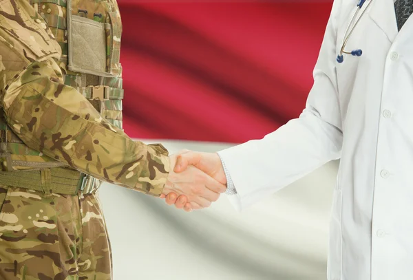 Military man in uniform and doctor shaking hands with national flag on background - Indonesia — Stok fotoğraf