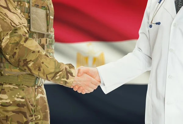 Homme militaire en uniforme et le médecin se serrant la main avec le drapeau national sur le fond - Egypte — Photo