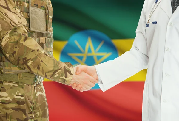 Homme militaire en uniforme et le médecin se serrant la main avec le drapeau national sur le fond - Ethiopie — Photo