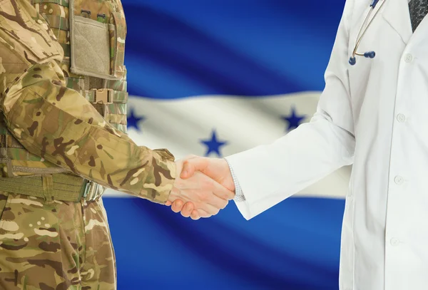 Homme militaire en uniforme et le médecin se serrant la main avec le drapeau national sur le fond - Honduras — Photo