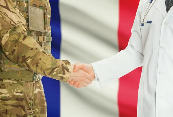 Military man in uniform and doctor shaking hands with national flag on background - France — Stock Photo, Image