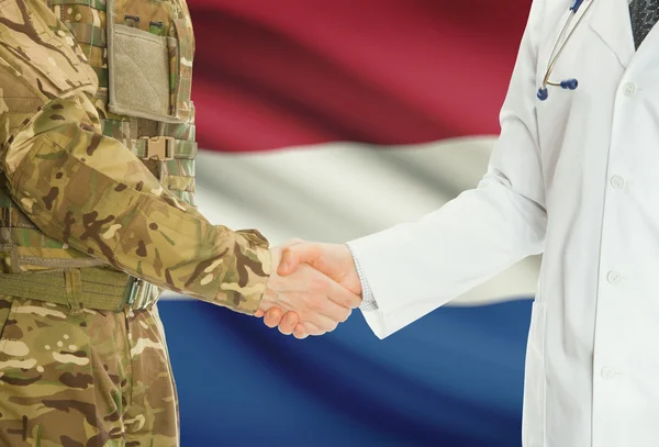 Military man in uniform and doctor shaking hands with national flag on background - Netherlands — Stok fotoğraf