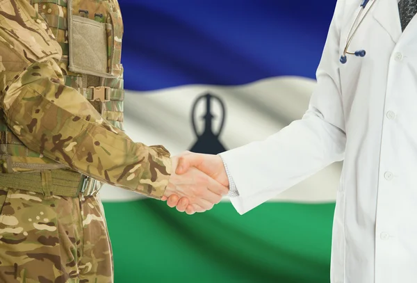 Military man in uniform and doctor shaking hands with national flag on background - Lesotho — Stock Photo, Image