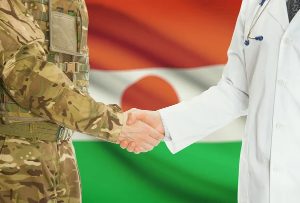 Military man in uniform and doctor shaking hands with national flag on background - Niger — 图库照片