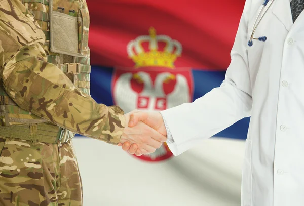 Homme militaire en uniforme et le médecin se serrant la main avec le drapeau national sur le fond - Serbie — Photo