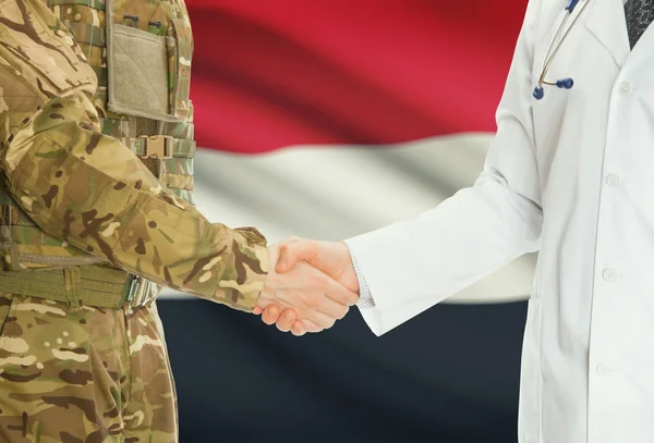 Military man in uniform and doctor shaking hands with national flag on background - Yemen — Stok fotoğraf