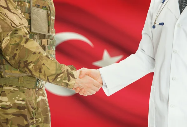 Homme militaire en uniforme et le médecin se serrant la main avec le drapeau national sur le fond - Turquie — Photo