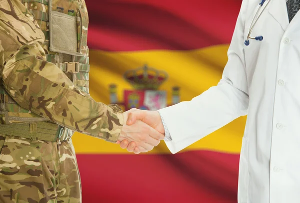 Military man in uniform and doctor shaking hands with national flag on background - Spain — 图库照片