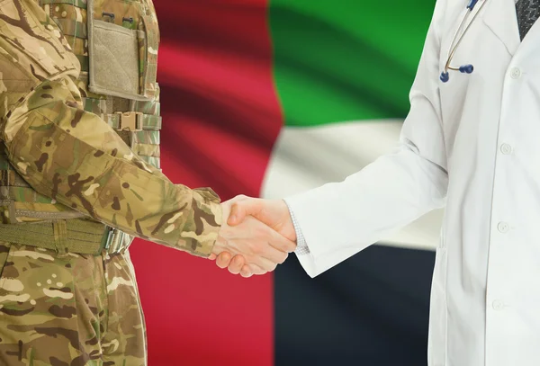 Homme militaire en uniforme et le médecin se serrant la main avec le drapeau national sur le fond - Emirats Arabes Unis — Photo