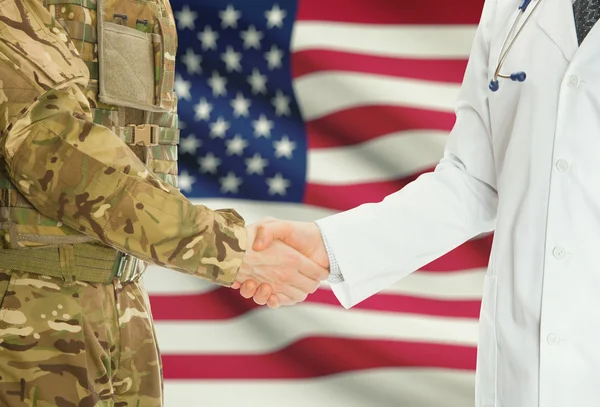 Military man in uniform and doctor shaking hands with national flag on background - United States — Stok fotoğraf